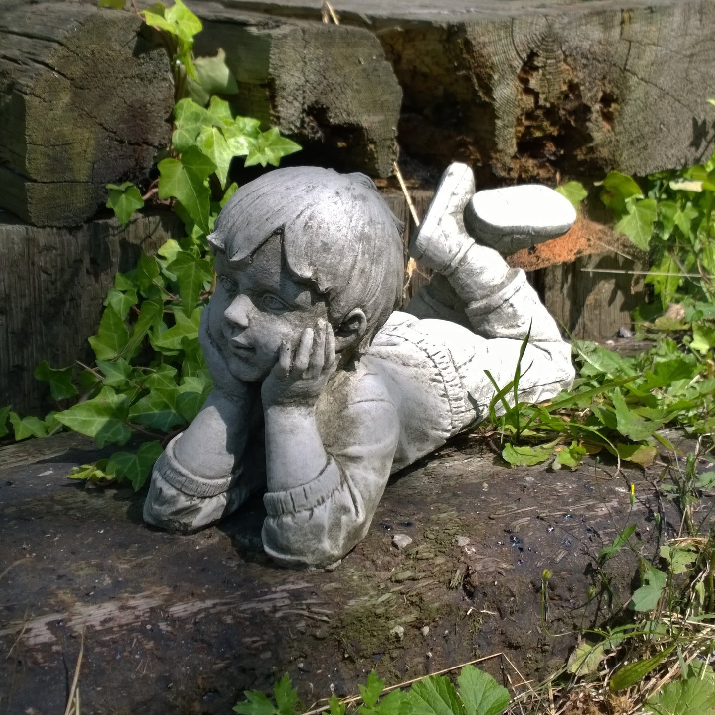 decorative garden statue of a boy holding a watering can with rustic finish on patio