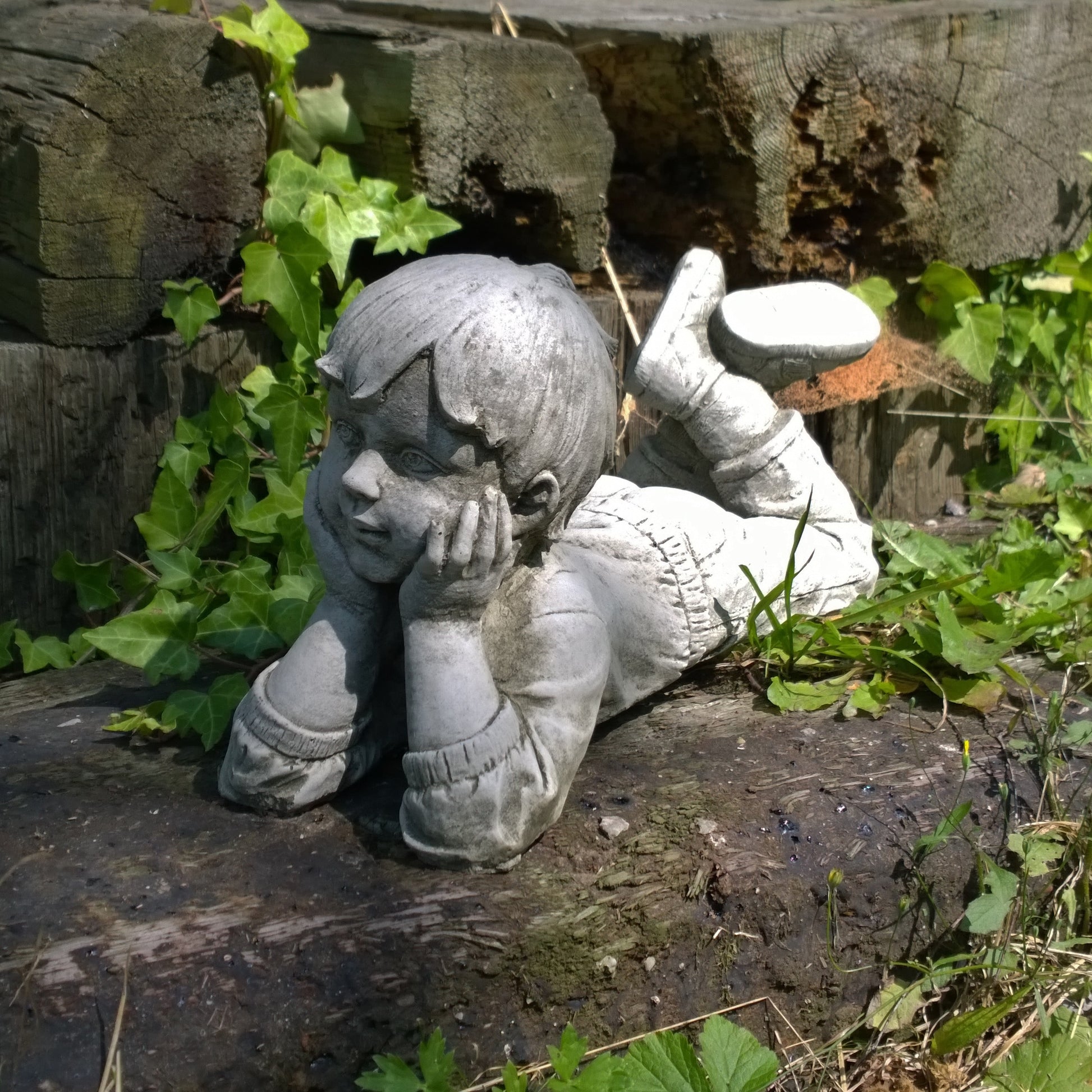 decorative garden statue of a boy holding a watering can with rustic finish on patio