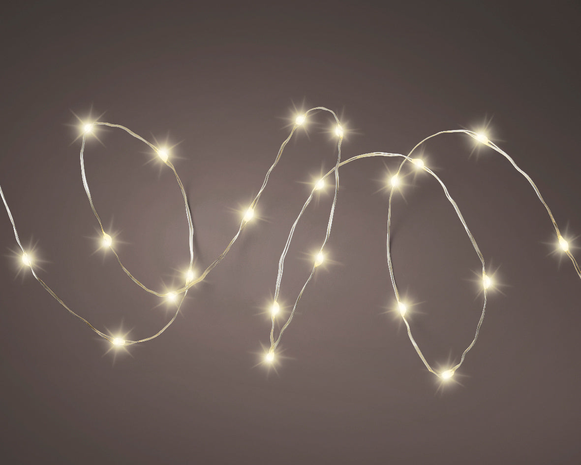 Warm white solar twinkle fairy string lights draped over garden fence at night