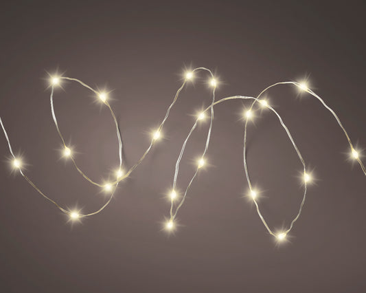Warm white solar twinkle fairy string lights draped over garden fence at night